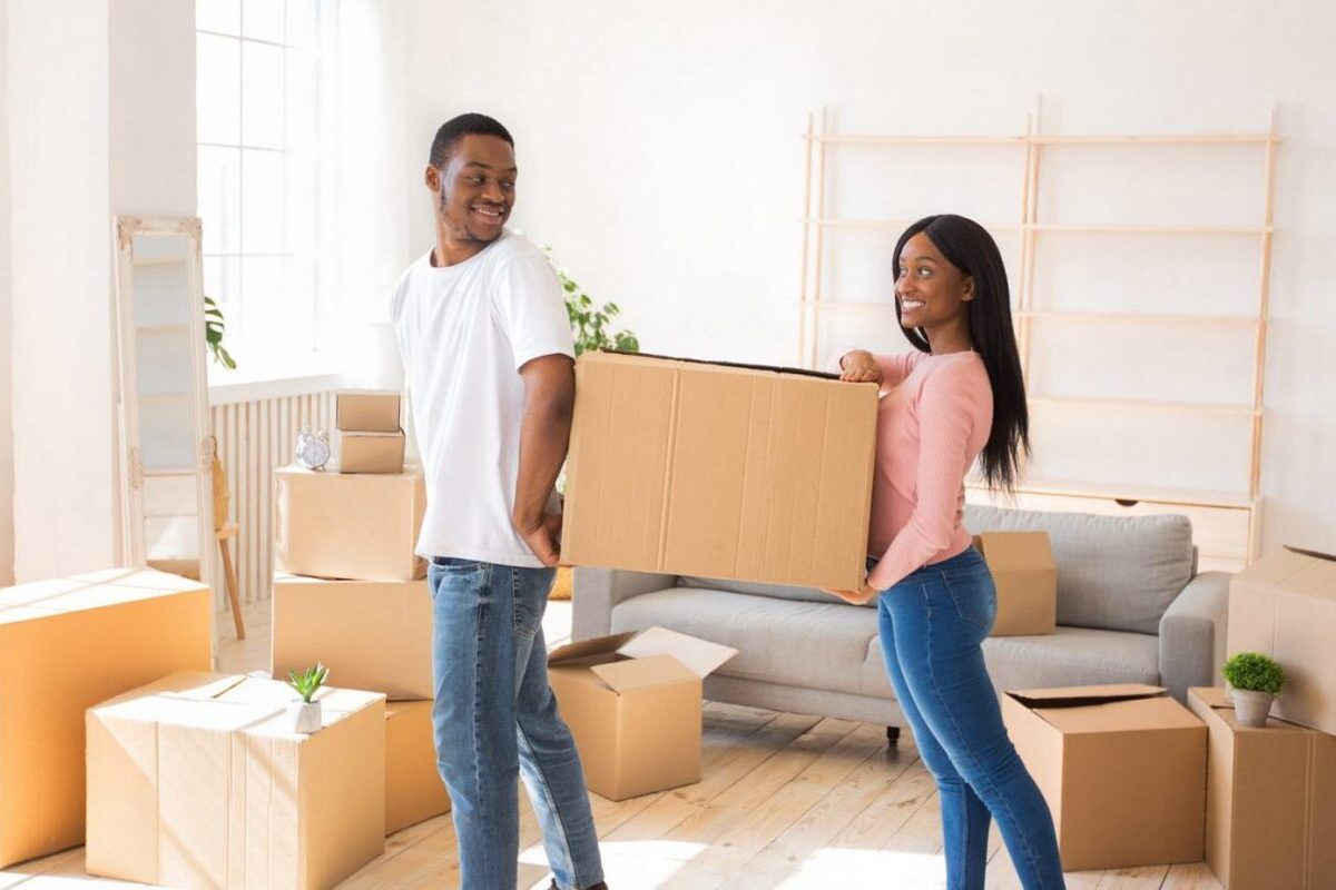 A young couple moves boxes out of their old house to put into their storage unit.