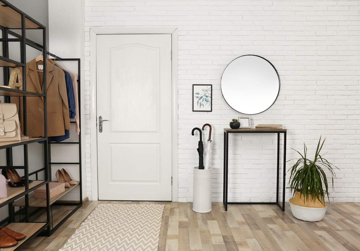 Photo of an organized home's entry space, including shelving space and umbrella stand.