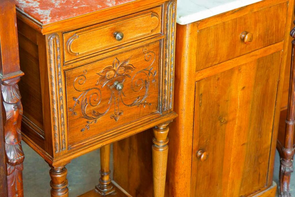 An antique, Italian, and wooden bedside table recently restored with floral decorations.