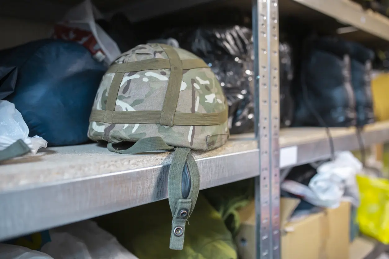 Military helmet and other gear sitting on shelves.