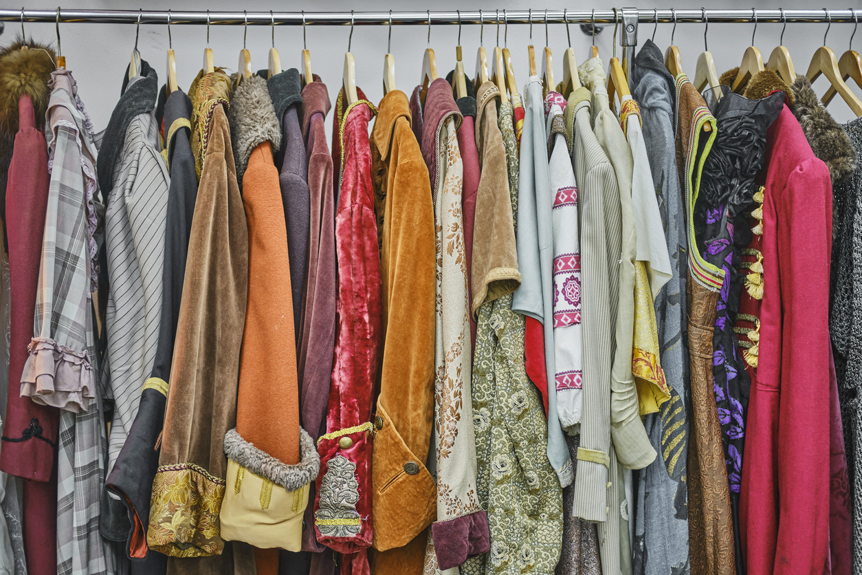 Vintage theatrical costumes hanging on a rod in a row in the dressing room.