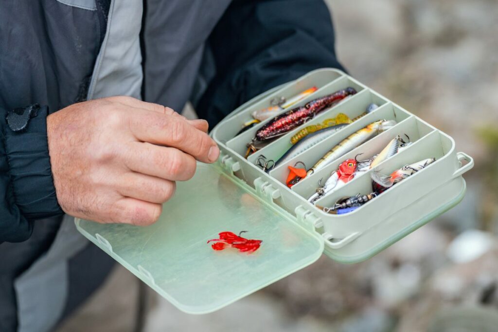 A plastic box of fishing items being held by a fisherman.