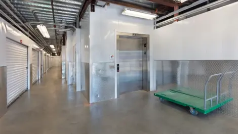 Elevator for storage facility with a push cart for boxes next to the door.