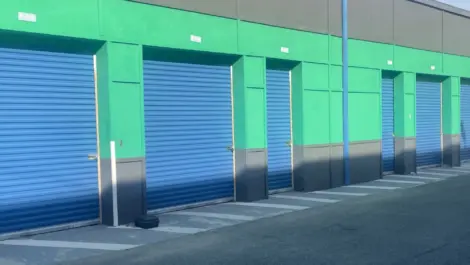 Outdoor storage units with blue doors and green and black exteriors.