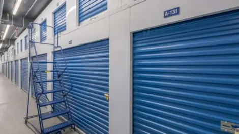 Indoor storage unit A-131 with a blue door and a ladder next to unit.