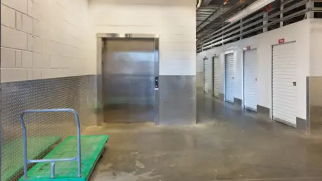 Storage facility elevator with green cart for moving boxes.