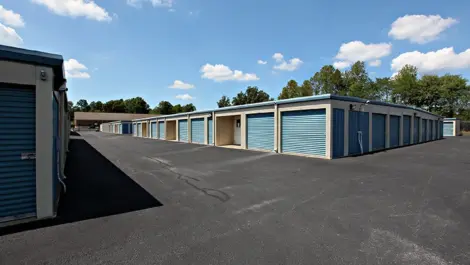 Storage units with blue doors on a paved road.