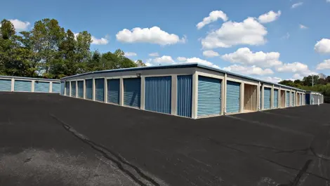 Multiple storage units with blue doors and a blue roof.