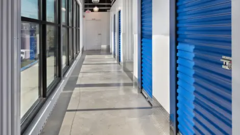 Hallway view of indoor storage units with a window view.