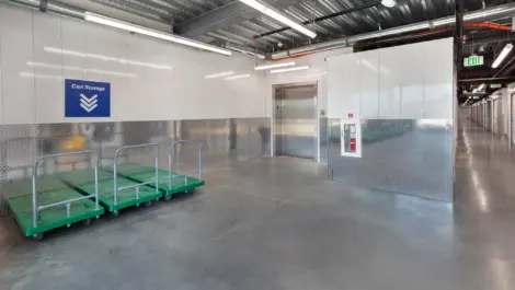 Inside storage facility with three green carts infront of elevator.