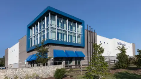 Storage facility building with a rockwall and wooden fence in the front.