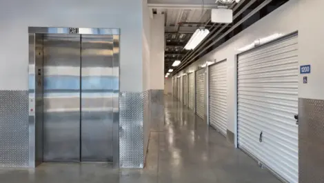 Elevator next to hallway of indoor storage units.