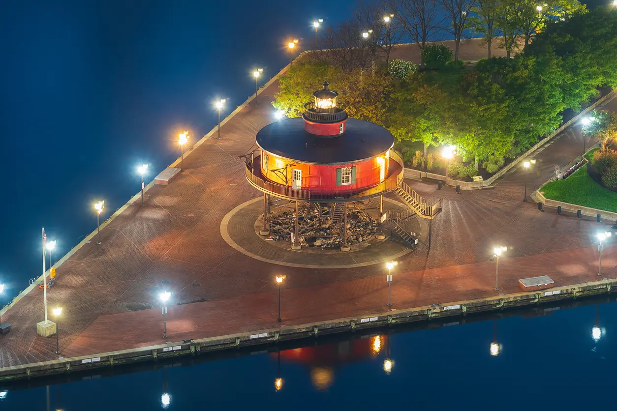 A red lighthouse illuminated at night at Baltimore’s Inner Harbor.