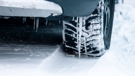 A winter tire covered in snow and ice as it travels down the road